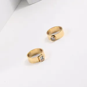 Macro detail view of two gold-plated stainless steel rings with square and round zircon stones.