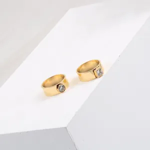Close-up detail of golden titanium steel rings featuring square and round zircon stones