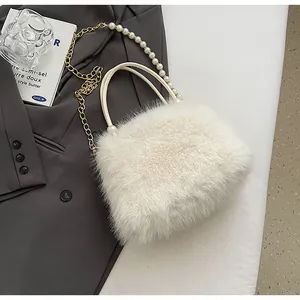 Close-up of off-white furry handbag with elegant pearl handle and gold chain strap details.