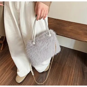 Macro shot of grey plush handbag featuring a pearl-decorated metal chain strap.