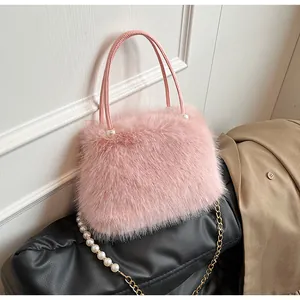 Detailed view of pink faux fur handbag featuring elegant pearl accents and gold chain.