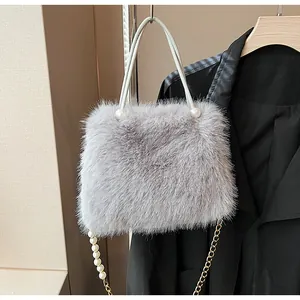 Detail of grey faux fur handbag with elegant pearl accents and gold chain strap.