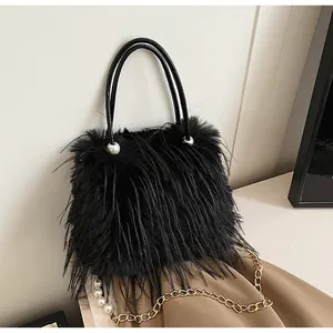 Close-up of stylish black faux fur handbag with gold chain strap and pearl detail