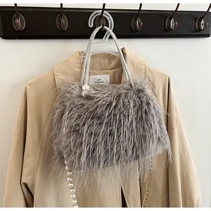 Grey faux fur handbag with pearl handle and gold chain strap hanging on a trench coat