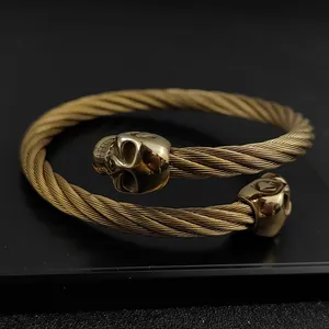 Detailed close-up view of a golden gothic twisted cable bracelet featuring double skulls
