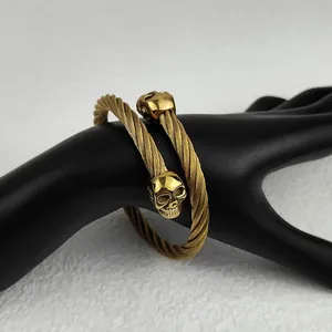 Detailed view of a golden gothic twisted rope cuff bracelet with dual skull heads.
