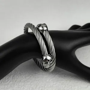 Detailed view of silver twisted cable bracelet with twin gothic skull charms