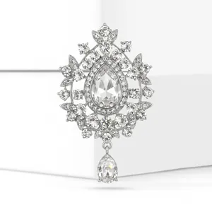 Macro detail view of a vintage silver brooch with brilliant clear crystals and a teardrop pendant.