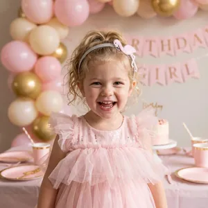 Bambina sorridente con fascia per capelli fenicottero rosa a una festa di compleanno