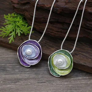Close-up of enamel rose pendants with pearls in elegant purple and green finishes.