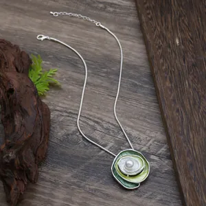 Detailed close-up view of an elegant green enamel rose pendant necklace with pearl.