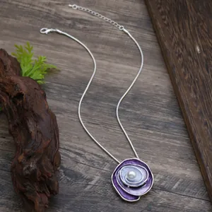 Elegant purple enamel rose necklace with pearl inlay on rustic wooden background
