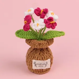 Charming handmade crochet flower pot with pink and white blossoms in a brown base.