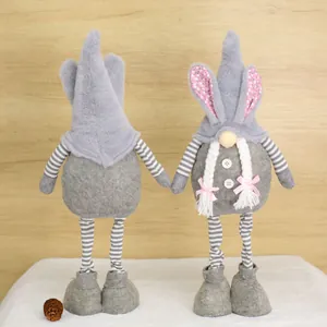 Detail view of two Easter bunny gnomes in grey plush with striped legs and braids.
