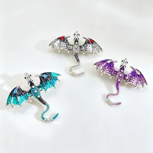 Detailed close-up showing three colorful fantasy dragon brooches with intricate wing patterns