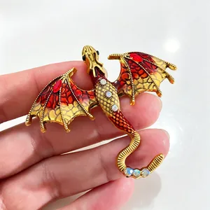 Macro detail of fantasy dragon brooch featuring vibrant red enamel wings and crystal accents