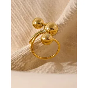 Elegant gold stainless steel open ring featuring three polished spheres on a textured fabric