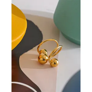 Minimalist golden stainless steel open ring featuring intersecting bands and polished spheres