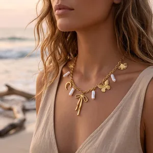 Elegant 18K gold-plated butterfly and pearl pendant necklace worn by woman at sunset beach
