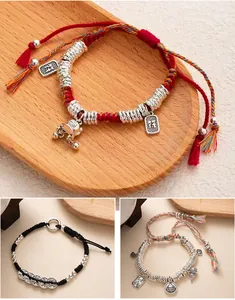 Detail view of three New Chinese style braided bracelets with silver charms and tassels.