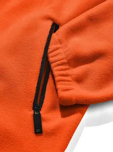 Close-up of men's orange polar fleece jacket with black zipper pocket and elastic cuff.
