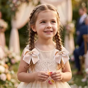 Bambina con eleganti fiocchi per capelli in nastro champagne e perle in giardino soleggiato