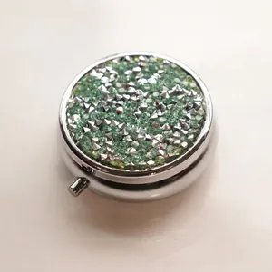 Portable round metal pill box with green rhinestones and silver spikes