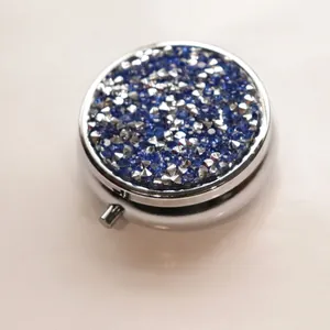 Portable round metal pill box decorated with sparkling blue and silver rhinestone inlay