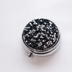 Elegant silver metal round pill box with sparkling black rhinestones for daily travel use