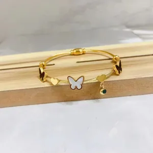 Detailed close-up of a gold stainless steel bracelet with butterfly and heart charms.