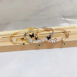 Detail of stainless steel cable bracelets with butterfly and heart charms in tri-color