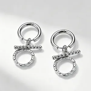 Macro detail shot showing the silver titanium steel earrings with unique textured OT clasp design.