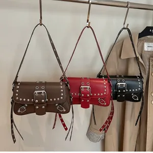Retro rivet motorcycle baguette shoulder bag in brown, red, and black hanging on a rack