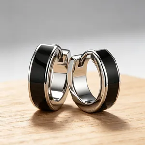Close-up macro view of minimalist stainless steel huggie hoop earrings with black enamel