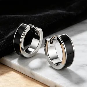 Detailed view of silver stainless steel huggie hoop earrings with black enamel inlay