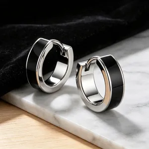 Macro detail of men's stainless steel hoop earrings with black enamel inlay