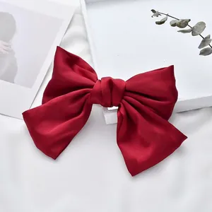 Close-up of a vibrant red satin oversized bow hair clip on a white background