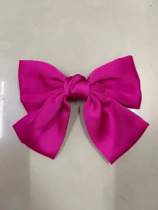 Macro view showcasing the vibrant fuchsia satin fabric and fold details of the bow