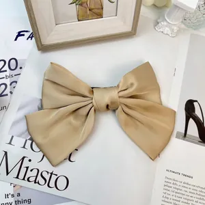 Close-up of a large champagne satin bow hair clip on a stylish magazine background