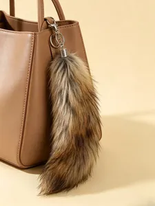 Close-up detail of a fluffy faux fur fox tail bag charm on a tan leather handbag