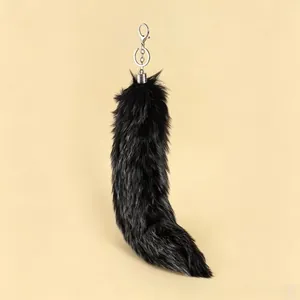 Detail of a luxury oversized black fox tail fur keychain with silver metal clasp.