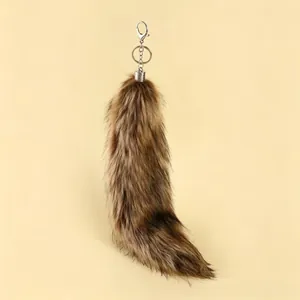 Macro detail of a fluffy fox tail keychain with a silver metal hook and ring clasp