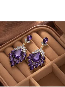 Detailed view of vintage purple crystal drop earrings in a luxury jewelry box