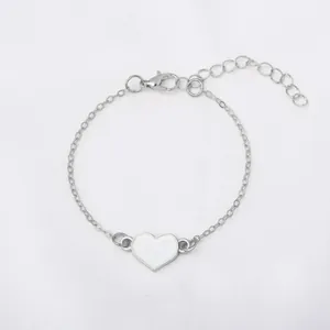 Elegante bracciale a catena argento con cuore in smalto bianco su tessuto bianco.