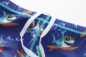 Détail en gros plan d'un short de bain bleu enfant avec imprimé requin et cordon blanc.