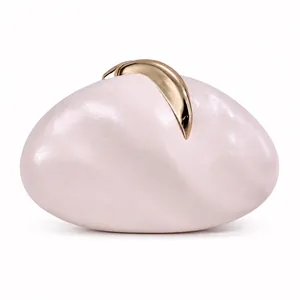 Close-up of pearl white pebble-shaped PU leather evening clutch with gold metal clasp