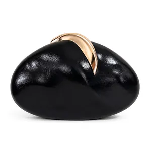Close-up of black PU evening clutch bag with elegant golden crescent-shaped hardware.