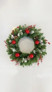 Detail of a Christmas wreath with pine needles, red berries, and frosted pine cones.