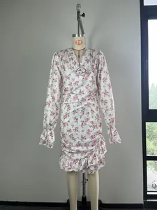 Détail d'une robe fleurie à manches longues montrant l'ourlet à volants et la taille froncée