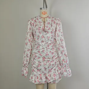 Détail d'une robe fleurie à col en V, corps froncé et poignets à volants sur mannequin.